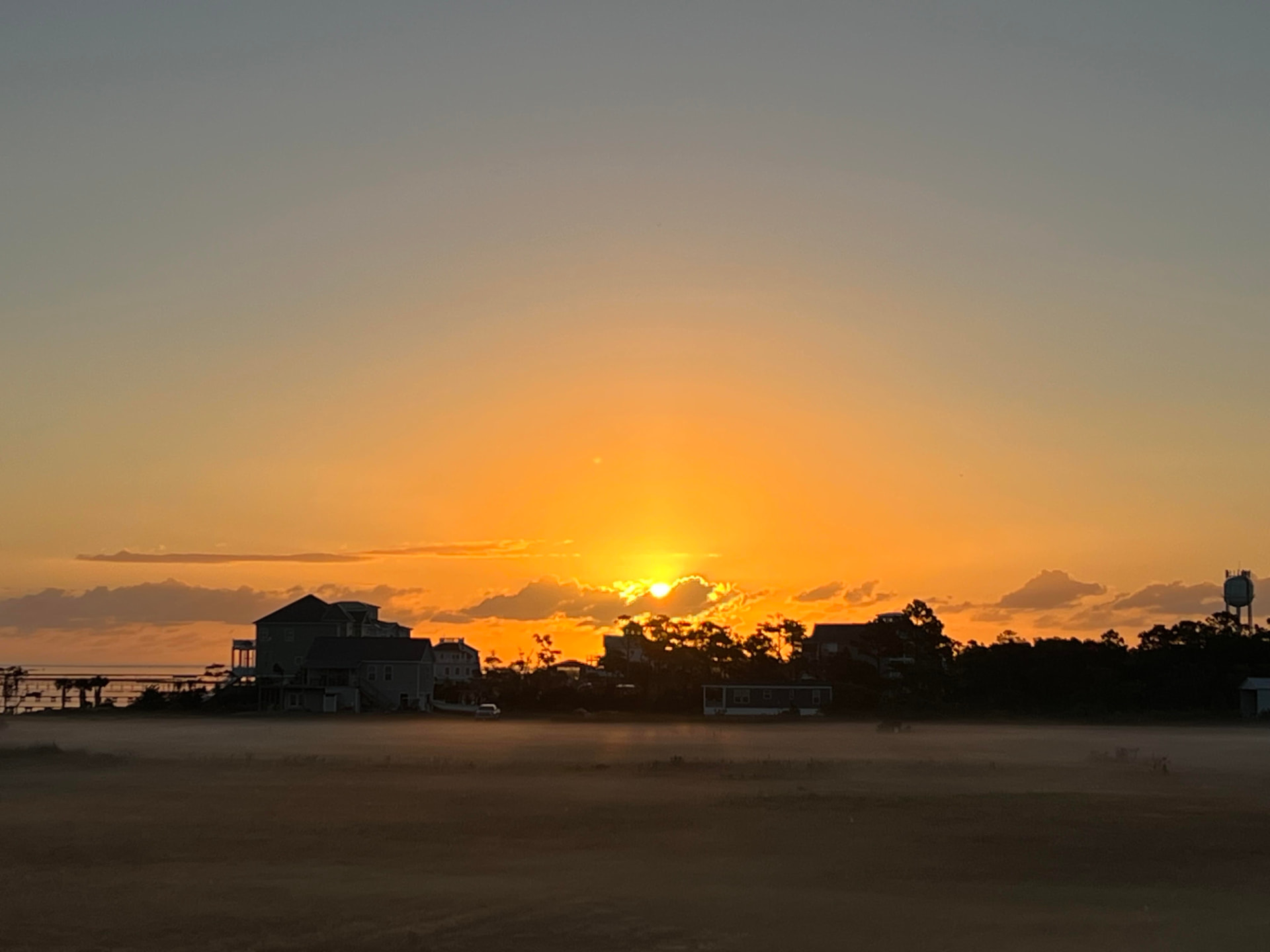 Golden sunset over a coastal community with beach houses along the shoreline